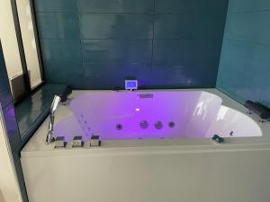 La salle de bains est pourvue d'une baignoire rose et de murs bleus. dans l'établissement appartement luxe balnéothérapie au village naturiste du cap d'agde, au Cap d'Agde