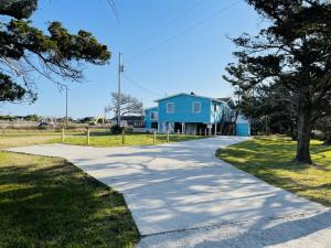 a driveway leading to a blue house at 57310 Eagle Pass Rd Home in Hatteras