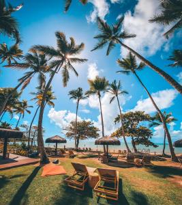 einen Strand mit Liegestühlen, Sonnenschirmen und Palmen in der Unterkunft Maion Hotel e Boutique in Praia do Espelho