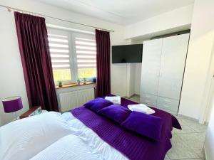 a bedroom with a large bed with purple sheets at Chrobry by Baltic Home in Międzyzdroje