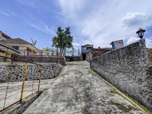 OYO Life 91116 Pelangi Residence Syariah في Jatiroke: جدار حجري مع بوابة بجانب شارع