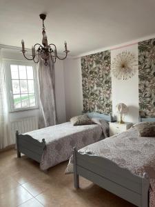 a bedroom with two beds and a chandelier at Hostel Arenos in Velilla del Río Carrión +16 photos