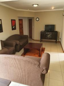a living room with two couches and a tv at Houghton Guest House in Johannesburg