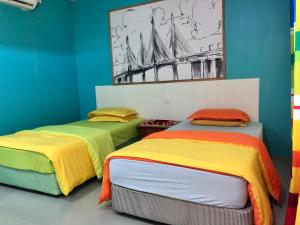 WAN'S ROOMSTAY LANGKAWI في بانتايْ سينانج: سريرين مع أغطية ملونة في الغرفة