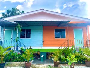 ein farbenfrohes Haus mit Pflanzen davor in der Unterkunft WAN'S ROOMSTAY LANGKAWI in Pantai Cenang