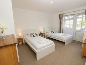 Habitación blanca con 2 camas y ventana en 8 Munday Cottages en Yarmouth