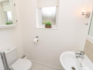 a white bathroom with a toilet and a sink at 8 Munday Cottages in Yarmouth +10 photos
