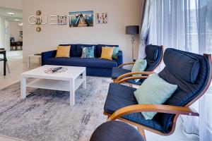uma sala de estar com um sofá azul e cadeiras em Shoreline The Palm, Free beach & pool access em Dubai