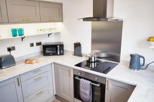 uma cozinha com armários brancos e um forno com placa de fogão em Parkway House - Modern with great transport links em Bristol