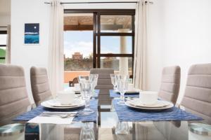 jadalnia ze stołem i krzesłami oraz oknem w obiekcie FTV Holidays Homes w Corralejo