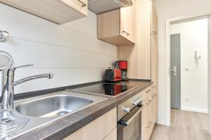 a kitchen with a stainless steel sink and wooden cabinets at SeeZeit Ferienwohnungen in Timmendorfer Strand