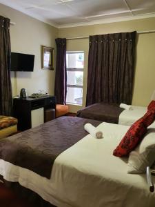 a hotel room with two beds and a desk at Houghton Guest House in Johannesburg