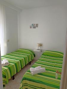 trois lits dans une chambre avec des draps verts et blancs dans l'établissement Casablanca - Playa Romana1, à Alcossebre