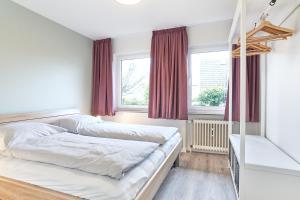 a bedroom with a bed and two windows at SeeZeit Ferienwohnungen in Timmendorfer Strand