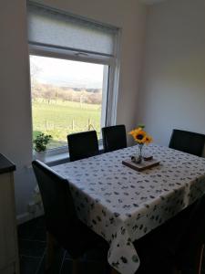 a dining room table with chairs and a window at Rural Cosy Three Bedroom Cottage in Girvan