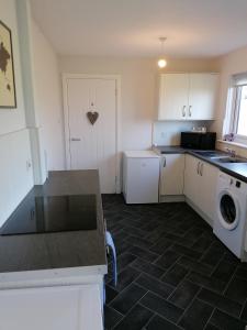 a kitchen with a washer and dryer in it at Rural Cosy Three Bedroom Cottage in Girvan