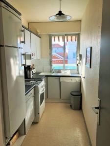 a kitchen with a white refrigerator and a window at JARDIN 308 Appartement avec Terrasse et Parking in Arcachon