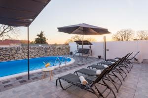 a group of chairs and an umbrella next to a pool at Kuća za odmor Cvita in Zadar