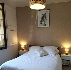 a bedroom with a white bed with two lamps and a picture at Le chant des hiboux in Haraucourt