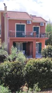 a large pink house with a large balcony at Villa Eleftheria in Karavomylos