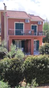 een groot roze huis met een groot balkon bij Villa Eleftheria in Karavomylos