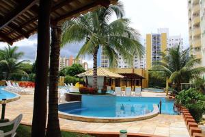 einen großen Pool mit Palmen und Stühlen in der Unterkunft 1406 AP 2 Quartos Shopping, Banheira de Hidro privativa , bebidas liberadas nas piscinas e internet no ap, proximo ao shopping singapura in Caldas Novas