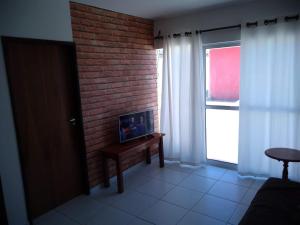 a living room with a brick wall and a window at Meu Cantinho na Praia do Frances in Marechal Deodoro
