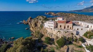 an old building on a cliff next to the ocean at Kedrodasos House in Elafonisi
