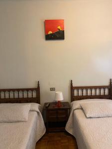 a bedroom with two beds and a table with a lamp at A lastra in Villamartín +7 photos