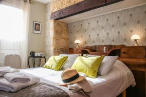 a bedroom with a bed with a hat on it at Aux Bories de Marquay, B&B avec piscine et SPA près de Sarlat in Marquay