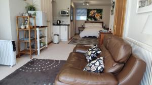 a living room with a leather couch and a bed at Wood Bank Studio Apartment in Holmfirth