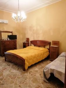 una camera con letto, mobili in legno e lampadario a braccio di Antica Dimora del Sole a Licata