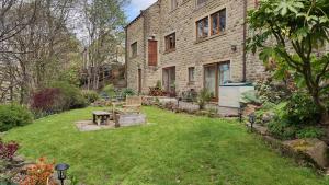 un patio trasero con una casa de ladrillo con césped en Wood Bank Studio Apartment, en Holmfirth