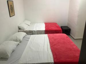 two beds in a room with red and white sheets at Hotel Buganvilla in Guaduas