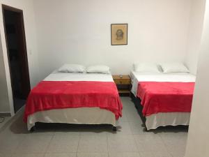 duas camas com lençóis vermelhos e brancos num quarto em Hotel Buganvilla em Guaduas