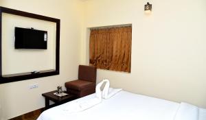 a bedroom with a bed and a chair and a mirror at Hotel R Inn Yercaud in Yercaud