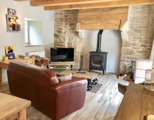 a living room with a leather couch and a fireplace at Usine du Moulin du Pont Neuf in Trégrom
