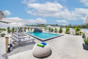 a pool at a resort with chairs and an umbrella at Santoterra Antigua Suites in Karterados