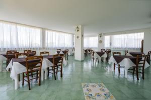 una sala da pranzo con tavoli, sedie e finestre di Villa Brunella ad Agropoli