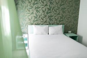 a bedroom with a white bed with a green wallpaper at Holidays Summer Vibes Apart Mamaia Nord in Năvodari