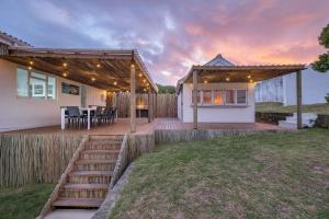 une terrasse en bois avec un grill et une maison dans l'établissement Live Simply Beach House, à Stilbaai