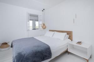 - une chambre blanche avec un grand lit et une table de nuit dans l'établissement Live Simply Beach House, à Stilbaai