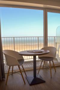 a table and two chairs in a room with a balcony at Hotel Sandeshoved Zeedijk in Nieuwpoort