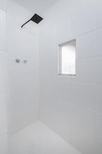 Cette chambre blanche dispose d'une fenêtre et d'un ventilateur de plafond. dans l'établissement Live Simply Beach House, à Stilbaai
