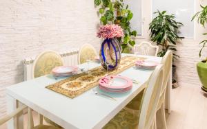 een witte eettafel met roze gerechten en een vaas met bloemen bij Luxury Apartment Sara in Umag