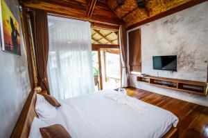 a bedroom with a white bed and a television at Tique Series Boutique Resort (SHA Extra Plus) in Ban Hat Lek