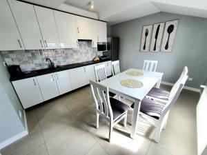 - une cuisine avec une table et des chaises blanches dans la chambre dans l'établissement Prestige Apartament, à Augustów