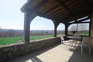 un patio avec une table et des chaises et un mur en pierre dans l'établissement Maison avec vue magnifique, à Loubejac
