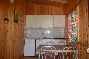 cocina con armarios blancos, mesa y sillas en camping feniglia, en Monte Argentario