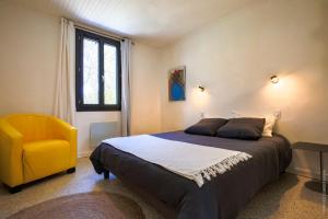 ein Schlafzimmer mit einem Bett und einem gelben Stuhl in der Unterkunft Maison dans les Arbres, SPA, Tennis, Parking in Nîmes